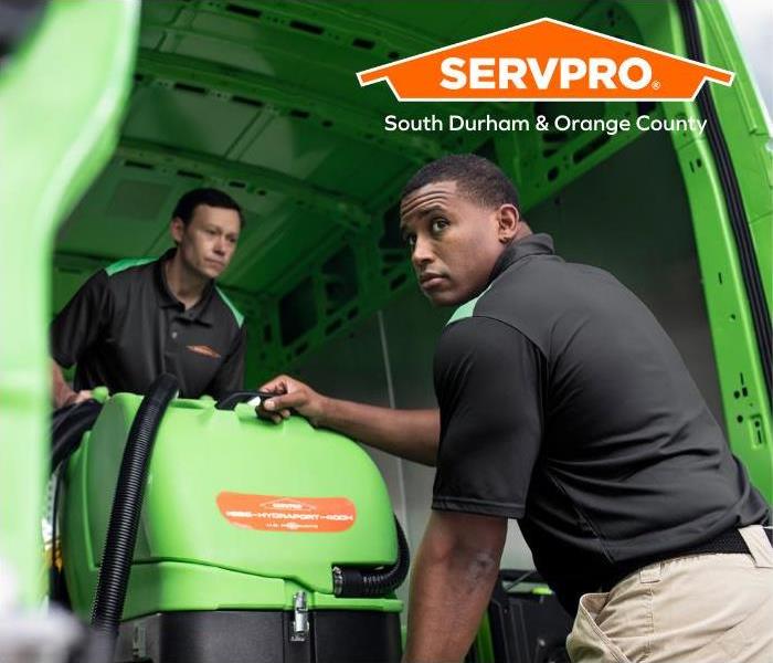 2 Employees loading a green piece of equipment 